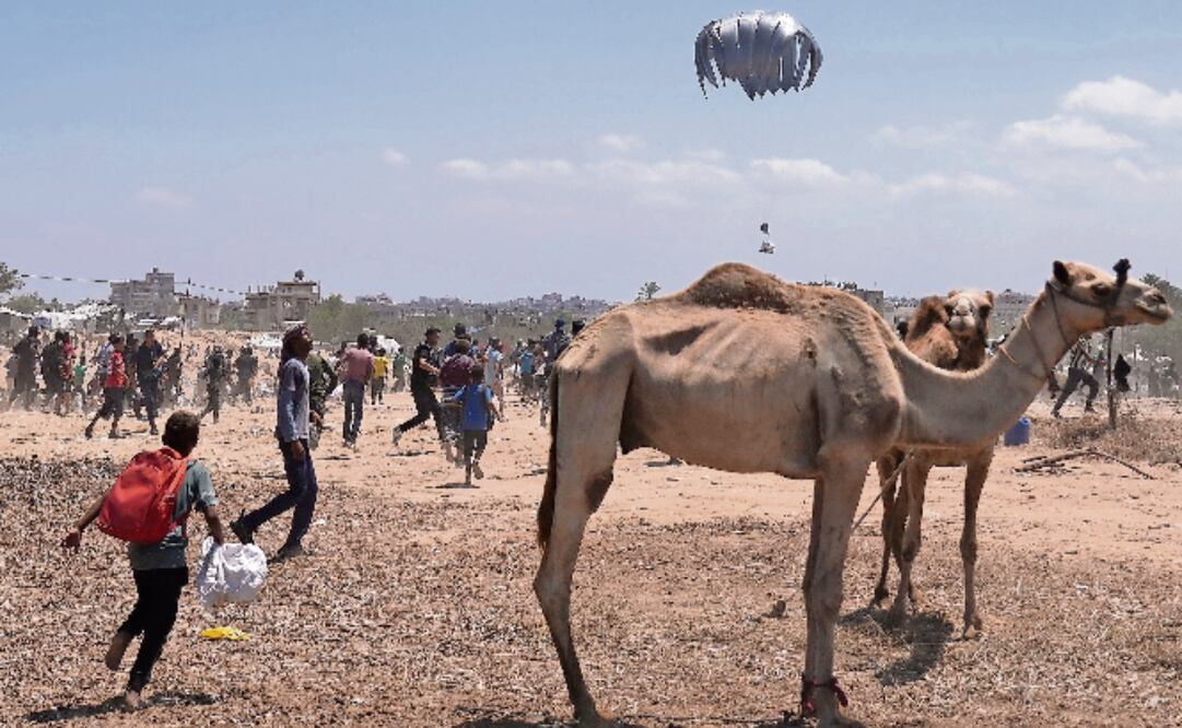 Palestinos corren para recoger ayuda humanitaria que varios países lanzaron desde el aire. Según Israel, 120 paquetes de comida fueron lanzados en las últimas horas, aunque la ONU afirma que es insuficiente y reclama acceso seguro a sus camiones. Con palos y puños, la gente defendió lo que había recolectado. Foto: Kareem Hana / AP