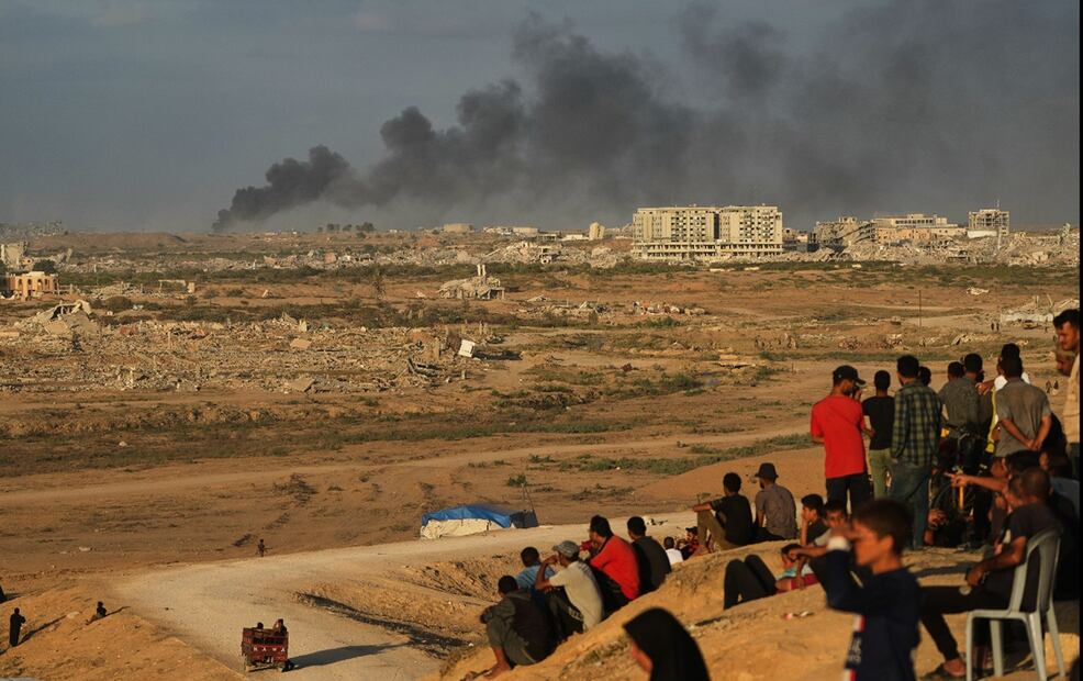 Palestinos desplazados observan la columna de humo que se eleva en la Ciudad de Gaza, tras los ataques militares israelíes, después del anuncio de la primera fase de un acuerdo de paz entre Israel y Hamas. Foto: AP