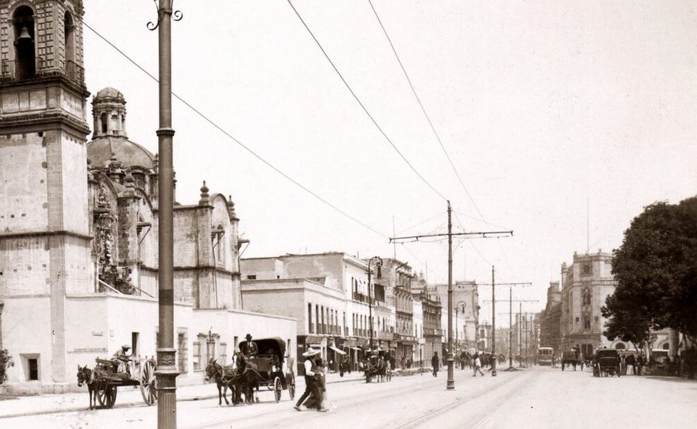 Panorámica de la Avenida Hidalgo, donde se observa la convivencia entre distintos medios de transporte, carruajes y automóviles. Del lado derecho se alcanza a ver el Palacio de Correos. Colección Carlos Villasana.