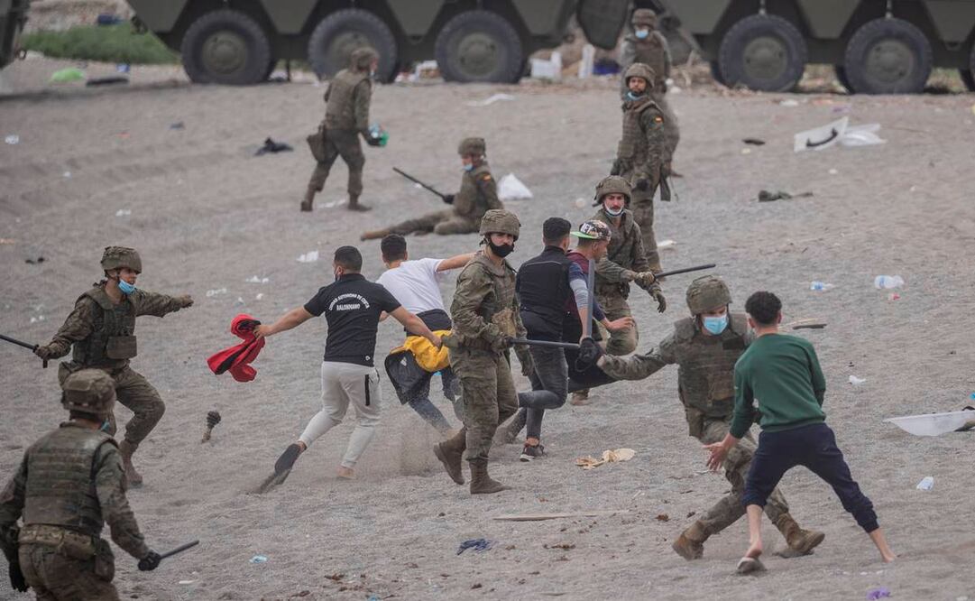 Soldados españoles vigilan la playa mientras los migrantes esperan en el enclave español de Ceuta, cerca de la frontera entre Marruecos y España. Foto: Bernat Armangue/AP.