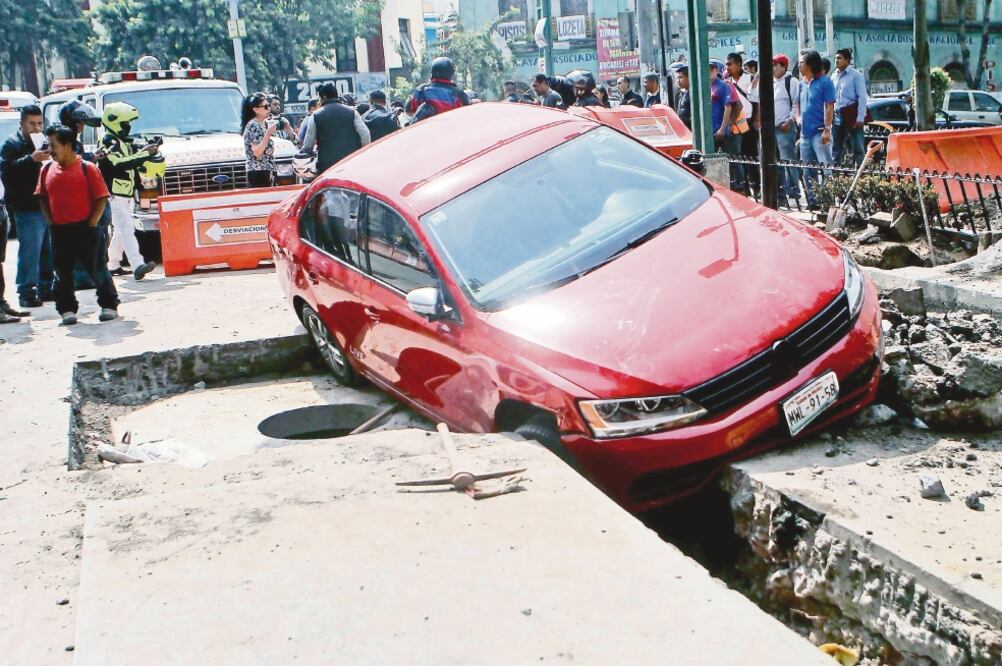 El auto tipo Jetta, color rojo, quedó atorado entre una de las zanjas que la CFE abrió para realizar trabajos de cableado subterráneo (FERNANDO RAMÍREZ. EL UNIVERSAL)