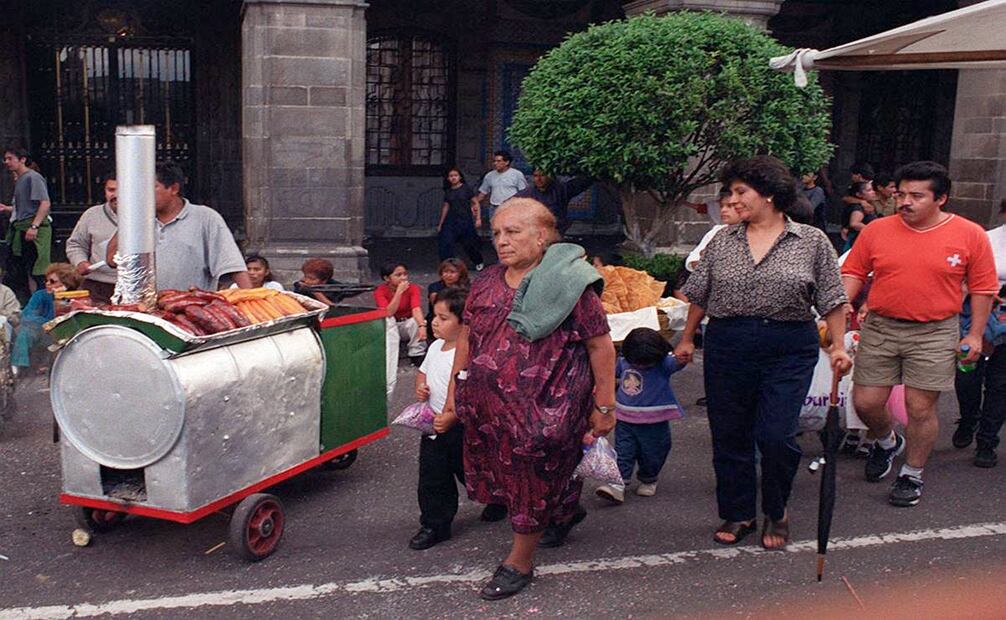 Esta imagen del 2001, cuando la capital aún era el Distrito Federal, sugiere que el carrito de camotes atrajo la atención de al menos dos peatones (der.). Archivo EL UNIVERSAL.