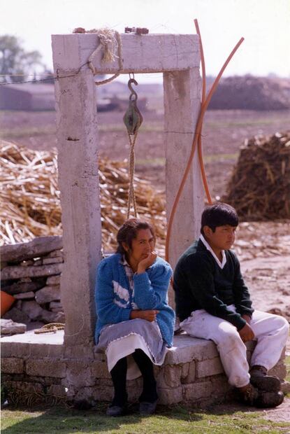 Un detalle que pocos mencionan de la experiencia de extraer agua de un pozo es que suele “pasarle factura” al cuerpo, por el esfuerzo que requiere. En la imagen, una mujer y un menor de edad descansan tras abastecerse. ESPECIAL.