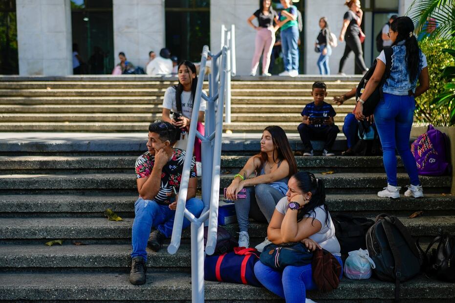 Trabajadores sentados afuera de su edificio de oficinas que cerró debido a un apagón en Caracas. Foto: AP