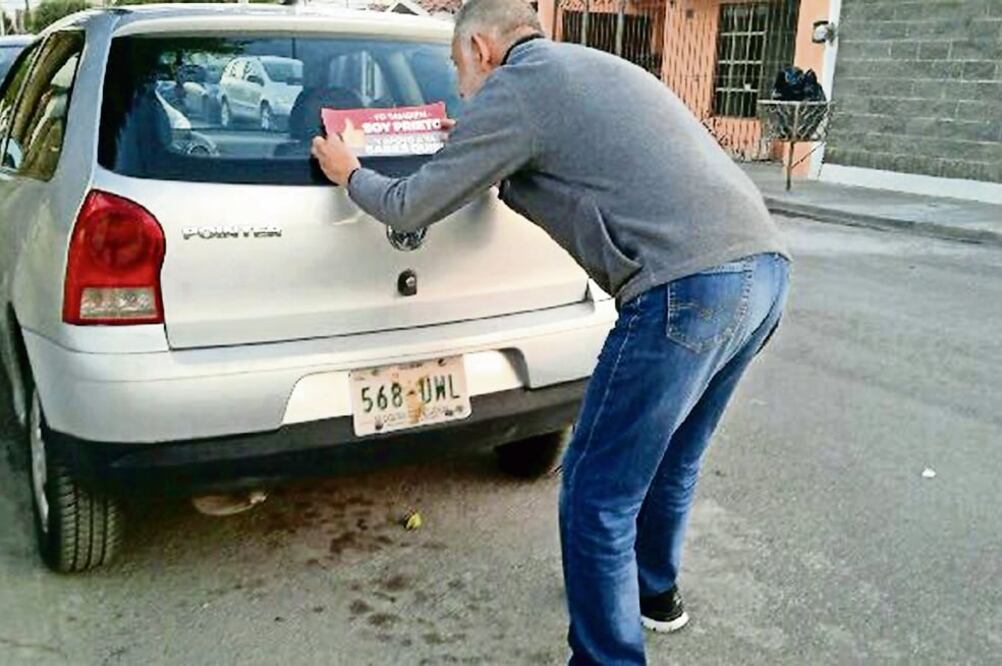 Brigadas de militantes de Morena pegan las calcomanías en la parte posterior de los vehículos, con previa aprobación de los conductores (ESPECIAL)