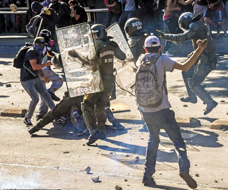 Al menos tres manifestantes acudieron al auxilio de otro inconforme que fue detenido por la policía durante las protestas en Santiago de Chile. MARTIN BERNETTI. AFP