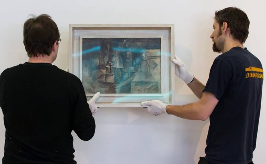 Empleados cuelgan en una de las paredes del Centro Pompidou el cuadro de Picasso "La coiffeuse". Foto: EFE