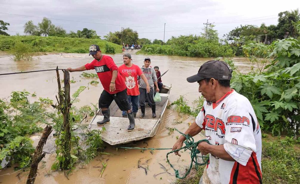 Habitantes de Campo Amapa, ubicado en la zona bananera de El Progreso, cruzan con sus pertenencias por un río en medio de las inundaciones causadas por la tormenta tropical Sara este sábado, en El Progreso, Honduras. Foto: EFE
