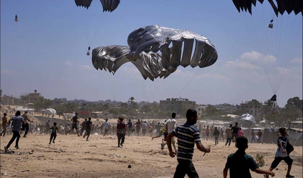 Palestinos corren a recoger ayuda humanitaria lanzada en paracaídas sobre Zawaida, en el centro de la Franja de Gaza. Foto: AP