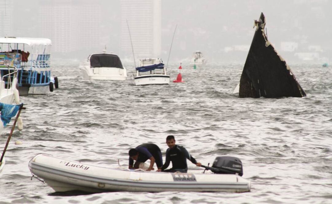Personas navegan junto a una embarcación hundida en Acapulco, Guerrero