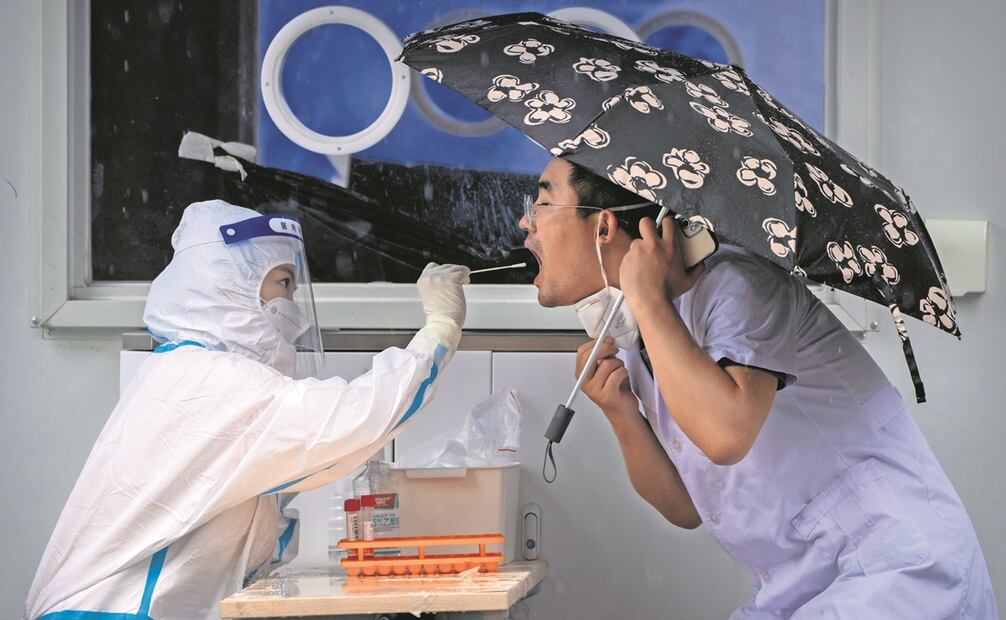 Un empleado sanitario, al tomar una muestra de la garganta de un hombre para una prueba de Covid-19 en Beijing, en junio de 2022, Foto: AP