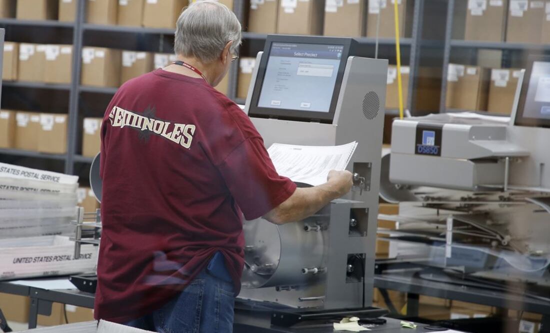 Un trabajador electoral introduce boletas en una máquina de tabulación en la oficina del Supervisor de Elecciones del Condado de Broward (Foto: AFP)