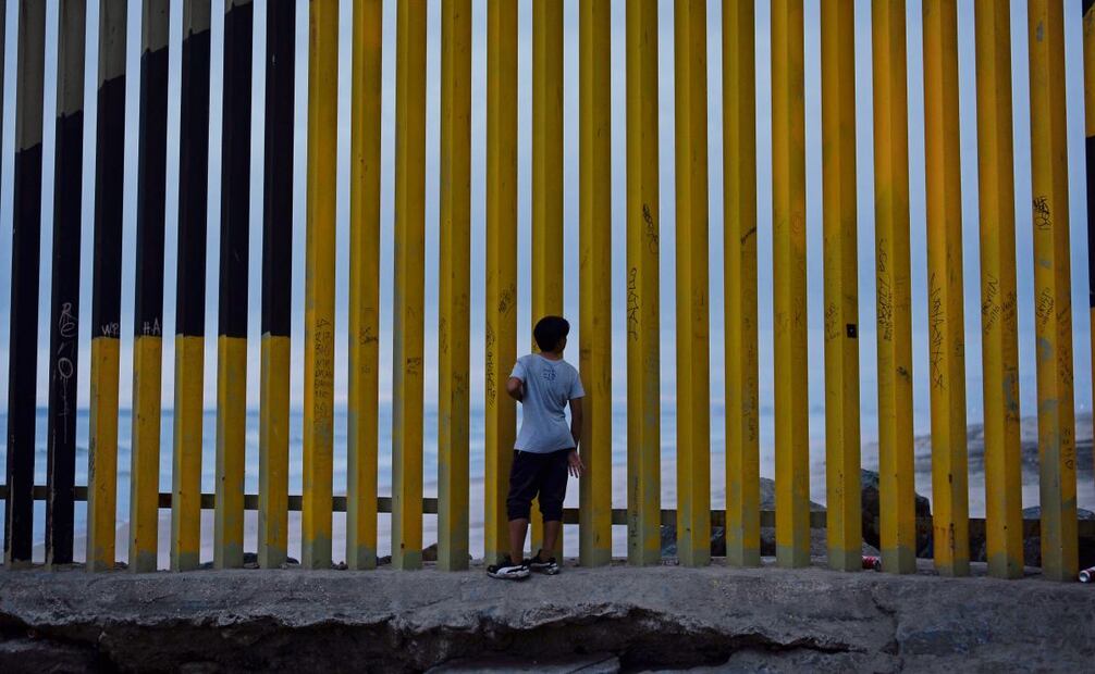 Un menor ve a través del muro fronterizo que separa a México de Estados Unidos, en Tijuana. Foto: Gregory Bull | AP (26/12/2024)