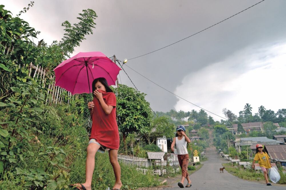 Lugareños se cubren la boca después de que el volcán Soputan hiciera erupción ayer, en la localidad indonesia de Kota Menara. (REUTERS)