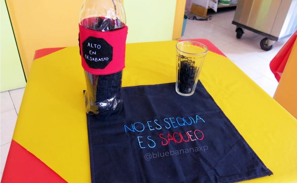 Servilleta “No es sequía, es saqueo” de Silvana Flores para Pongamos el Tema sobre la Mesa; el envase y vaso tienen hilo que simula el refresco. Foto: Cortesía Ari Zantiago/Poniendo el Tema sobre la Mesa/ESPECIAL.