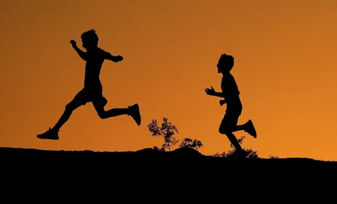 La silueta de dos niños se ve recortada contra el cielo al atardecer mientras corren por una colina en el Parque Papago, el 1 de abril de 2022 en Phoenix. Foto: AP