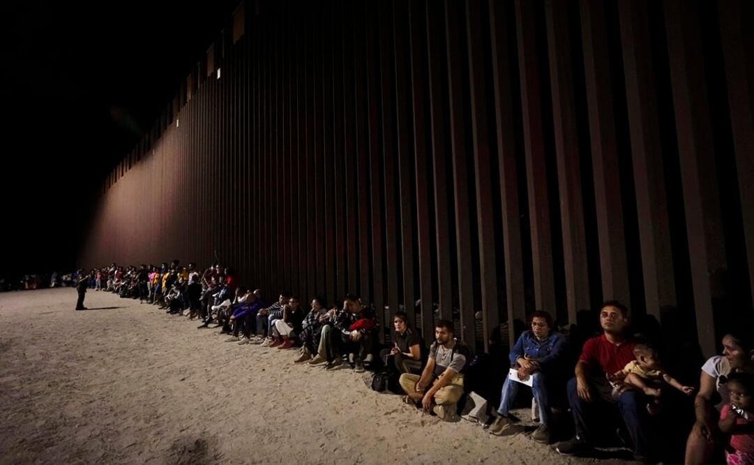 Migrantes junto a un muro fronterizo cerca de Yuma, Arizona, después de cruzar desde México. Foto: AP
