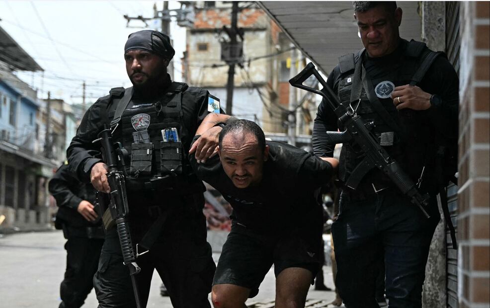 Policías escoltan a un sospechoso arrestados durante la Operación Contención fuera de la favela Vila Cruzeiro, en el complejo Penha, Río de Janeiro, Brasil, el 28 de octubre de 2025. Foto: AFP