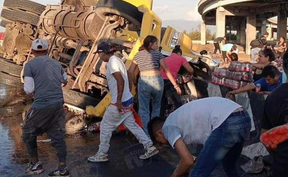 El tráiler quedó recostado sobre su costado izquierdo y la mercancía cayó sobre el pavimento, por lo que la gente comenzó a llevársela. Foto: Especial