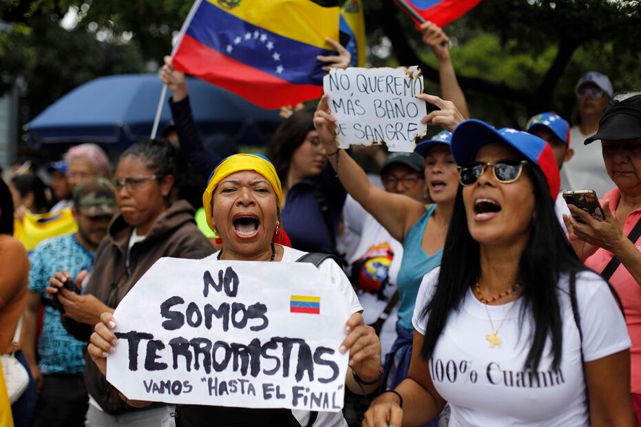 Una mujer sostiene una cartulina con el mensaje: "No somos terroristas" mientras espera con sus compañeros la llegada de la lideresa opositora María Corina Machado, a Caracas, Venezuela, el sábado 3 de agosto de 2024. Foto: AP