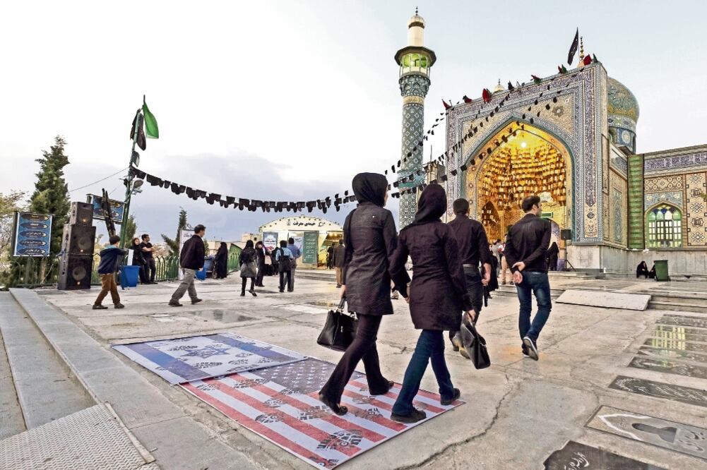 Iraníes pasan sobre las banderas de EU e Israel, en una mezquita en el norte de Teherán. Las relaciones de Irán con esos países no son buenas. (REUTERS)