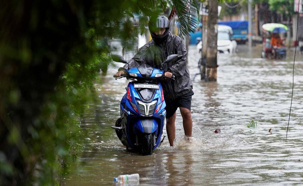 Los viajeros caminan por una calle inundada tras las fuertes lluvias monzónicas en Guwahati, el miércoles 13 de agosto de 2025. Foto: AP