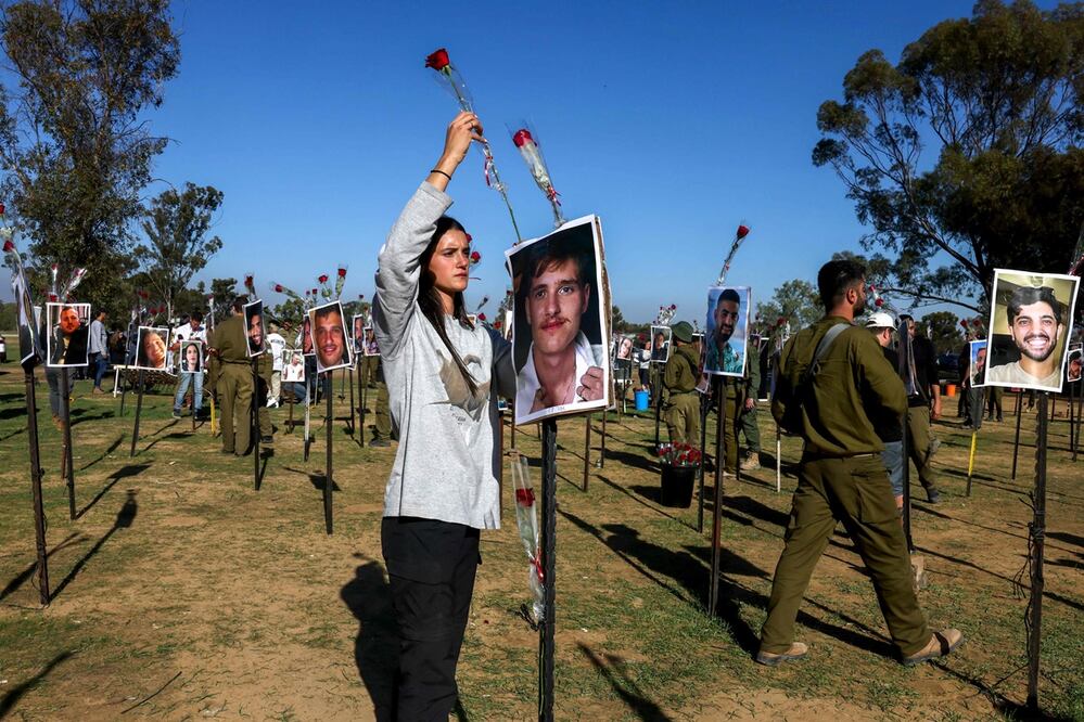 Una israelí coloca una rosa, mientras presenta sus respetos en una instalación con fotografías de jóvenes que fueron asesinados o secuestrados durante el ataque del 7 de octubre por militantes de Hamas de la Franja de Gaza, en el lugar del festival Nova, en Re'im. Foto: AFP