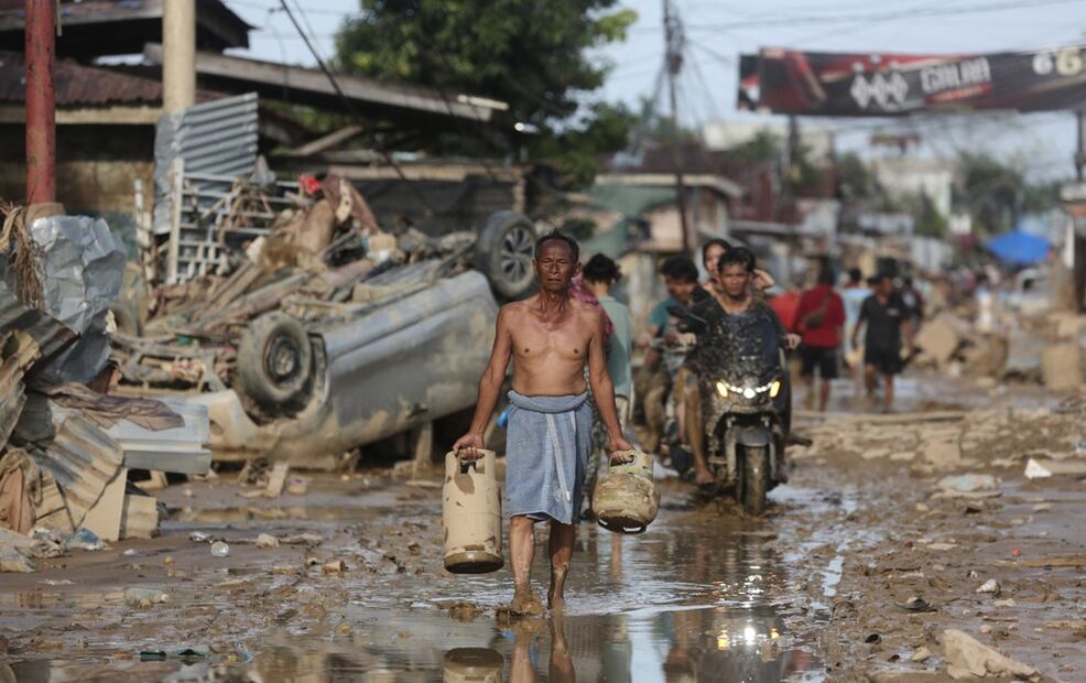Un sobreviviente lleva cilindros de gas recuperados en una zona afectada por las inundaciones en Aceh Tamiang, en la isla de Sumatra, Indonesia, el jueves 4 de diciembre de 2025. Foto: AP