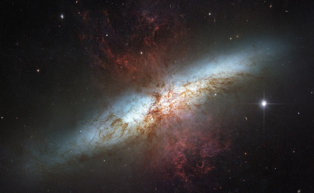Penachos de brillante explosión de hidrógeno desde el núcleo central de esta enérgica galaxia. Las estrellas nacen en el centro de la galaxia 10 veces más rápido que en nuestra propia Vía Láctea.