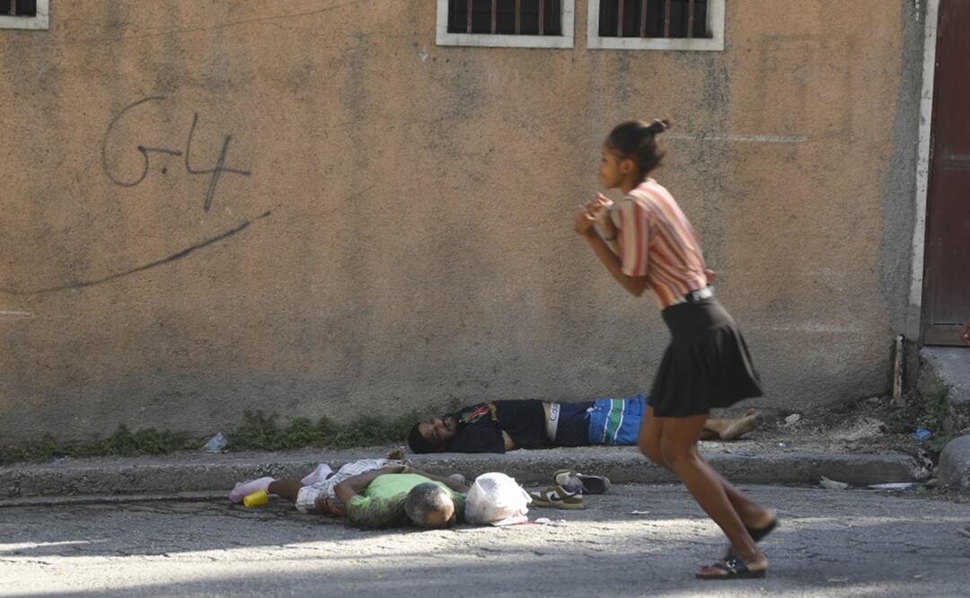 Una mujer pasa junto a los cuerpos de dos hombres asesinados por agresores desconocidos en Puerto Príncipe, Haití. Foto: AP