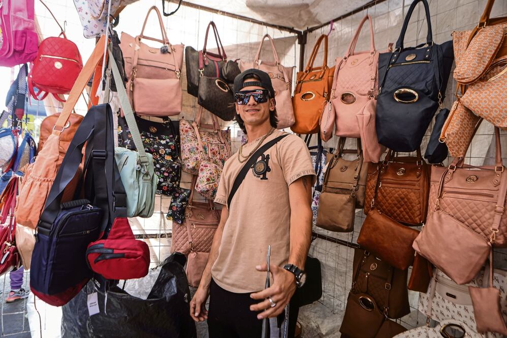 Con sus lentes oscuros, el venezolano Reynen Chirino, a quien sus compañeros le hacen bromas por su parecido con el cantante Peso Pluma, vende bolsas de imitación en el barrio de Tepito. Gabriel Pano | El Universal