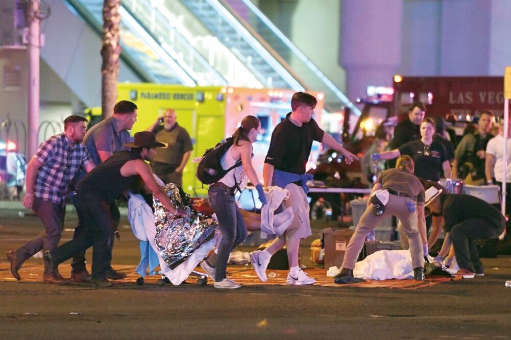 Una persona es atendida en la calle tras el ataque en un concierto de Las Vegas. La gente usó sus automóviles para trasladar a los lesionados a hospitales. (DAVID BECKER. AFP)