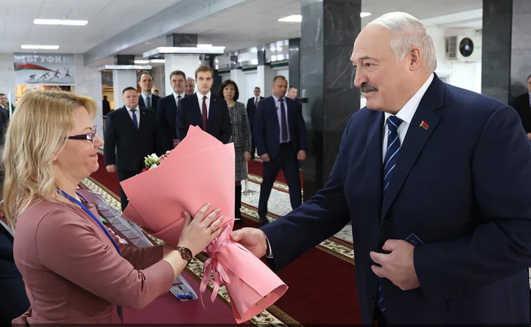El presidente de Bielorrusia, Alexander Lukashenko, entrega flores a una funcionaria de la comisión electoral antes de votar en un centro electoral en Minsk, Bielorrusia. Foto: AP