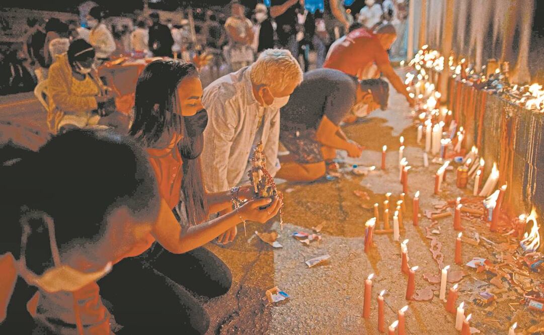 Fieles rezan frente a la iglesia de San Jorge, cerrada para frenar los contagios de coronavirus, en el barrio de Quintino de Río de Janeiro. Foto: Mauro Pimentel/ AFP.