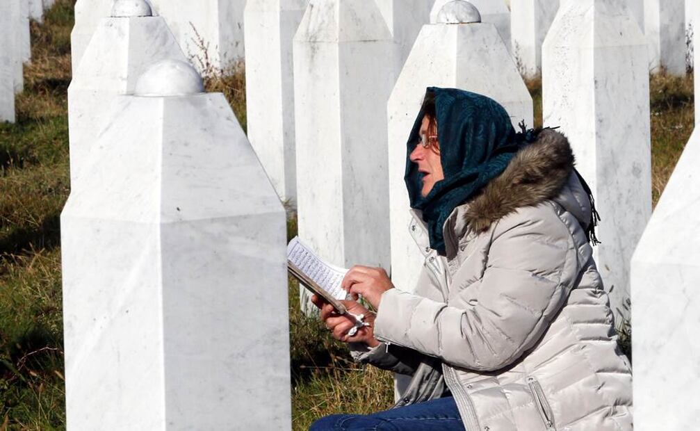 Una mujer lee una oración a un familiar enterrado en el Monumento del Genocidio de Srebrenica. Foto: EFE