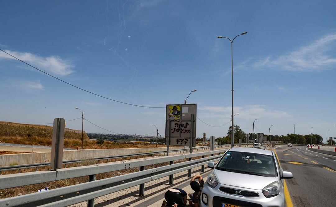 La gente se cubre mientras los misiles del sistema de defensa aérea Cúpula de Hierro de Israel interceptan cohetes disparados por el grupo Hamas. FOTO: AFP