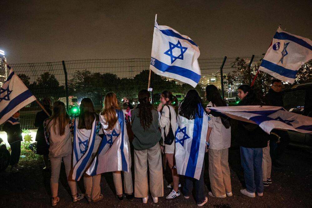 Israelíes ondean banderas de Israel junto al Hospital Schneider mientras esperan la liberación de rehenes en Petah Tikva, cerca de Tel Aviv, el 26 de noviembre de 2023. FOTO: AFP