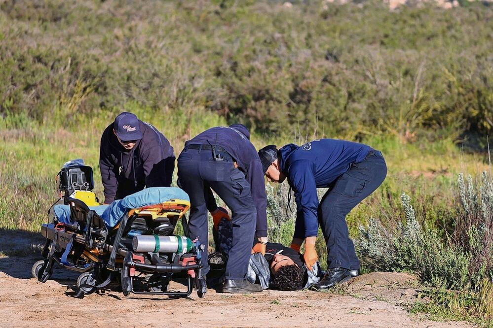 Los socorristas ayudan a una persona, mientras decenas de solicitantes de asilo esperan cerca de la frontera entre EU y México en Campo, California. Foto: de D avid Swanson. AFP