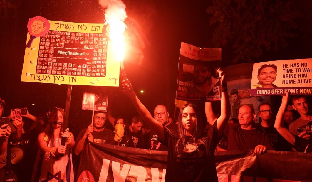 Familiares y partidarios de israelíes tomados como rehenes por militantes palestinos en Gaza en los ataques del 7 de octubre encienden bengalas y sostienen retratos de los tomados durante una protesta pidiendo su liberación. Foto: AFP