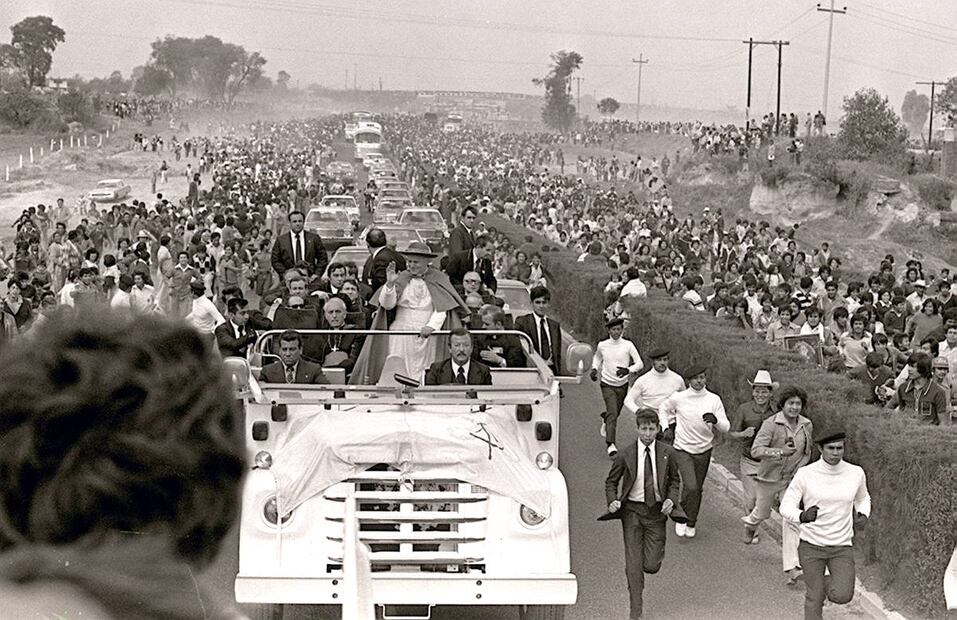 Al igual que lo habían hecho por dos días en el DF, los escoltas de a pie acompañaron el trayecto del autobús de Juan Pablo II en su viaje a Puebla de los Ángeles, el 28 de enero de 1979. No faltaron los curiosos que siguieron la caminata, como tampoco las familias que llevaron imágenes de santos a la orilla de la carretera México-Puebla. Archivo EL UNIVERSAL.