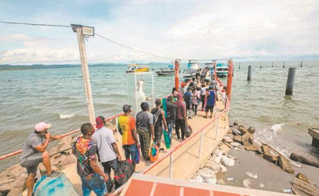 Migrantes irregulares latinoamericanos, asiáticos y africanos caminan por un muelle del norte de Colombia sobre el mar Caribe para abordar unas lanchas que los acerquen a Panamá. Foto: PERIÓDICO EL COLOMBIANO, DE MEDELLÍN