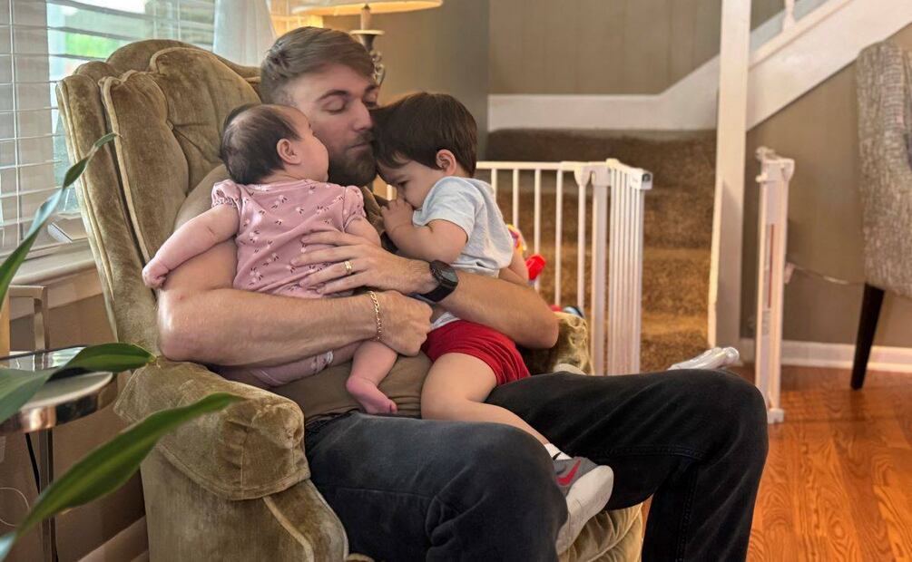 El veterano del Cuerpo de Marines de Estados Unidos, Adrian Clouatre, carga a su hija de 3 meses de edad, Lyn, y a su hijo de casi 2 años de edad, Noah, en su residencia, el 17 de junio de 2025, en Baton Rouge, Luisiana. (AP Foto/Stephen Smith, Archivo)
