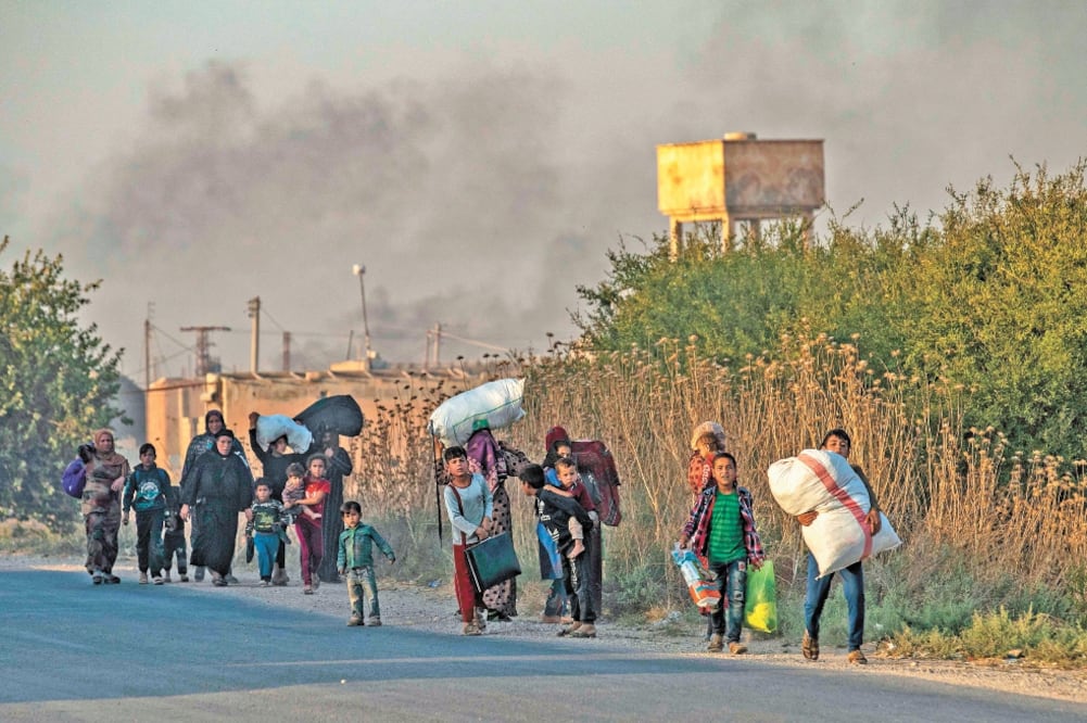 Habitantes huyen de los bombardeos registrados ayer por parte de las fuerzas turcas en Ras al Ain, noreste de Siria. Foto: DELIL SOULEIMAN. AFP