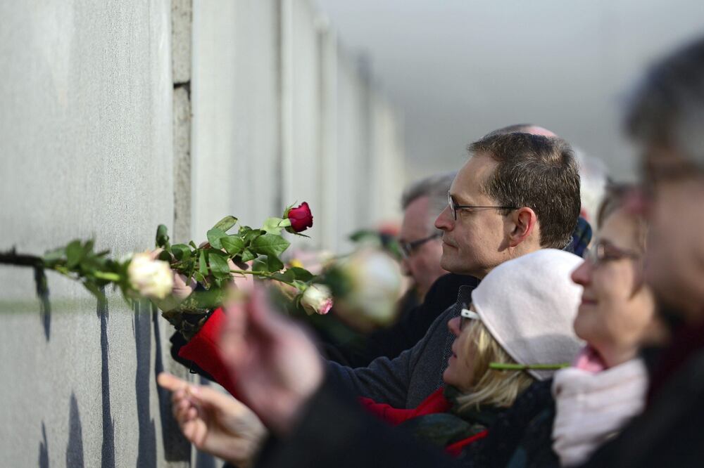 El alcalde de Berlín, Michael Müller, coloca rosas en una grieta del muro durante un evento para conmemorar la revolución pacífica de 1989. (FOTO: EFE)