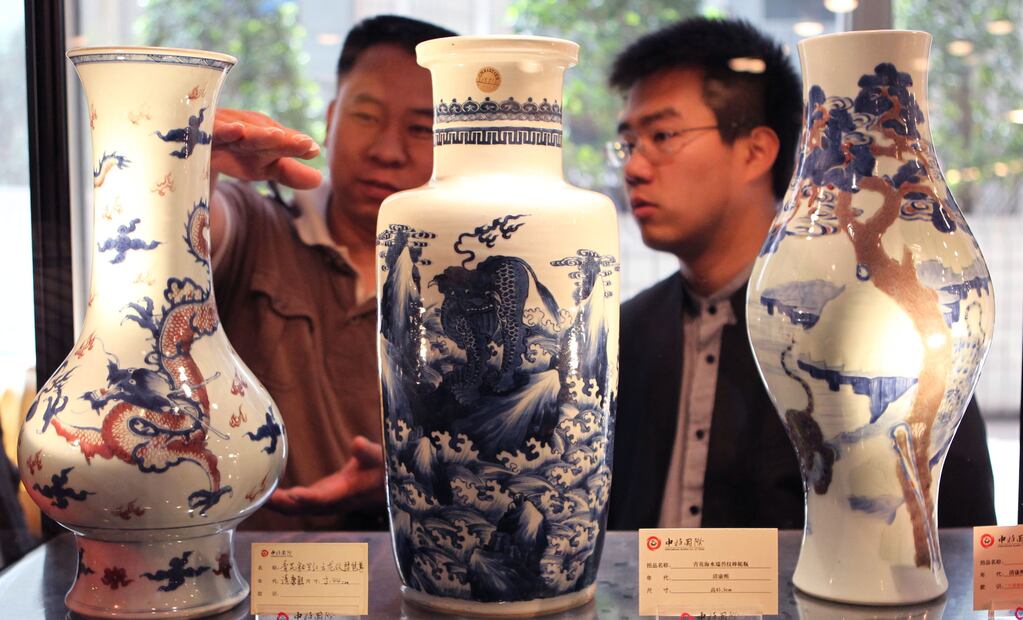 Un par de ciudadanos observa tres de las piezas de porcelana de la dinastía Ching (1636-1911) que estaban listas para ser rematadas en Beijing, en 2011. Foto: Xinhua/Zhang Yanhui.
