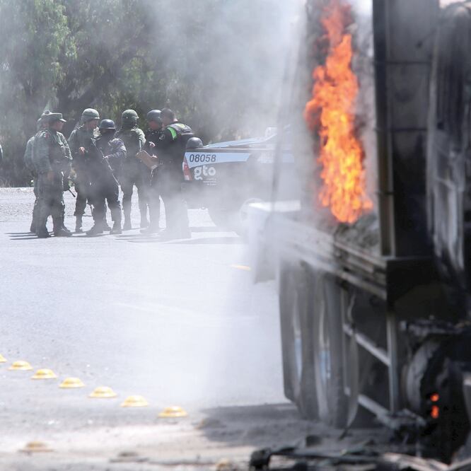 Policías y militares observan un camión incendiado por lugareños en una carretera de Comonfort, Guanajuato, contra el operativo en Santa Rosa de Lima. SERGIO MALDONADO. REUTERS