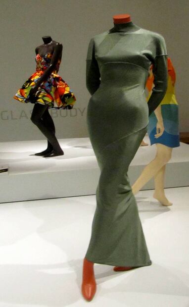 Al frente en la imagen, un vestido en fibra de acetato, obra de Azzedine Alaïa, que acaparó la atención internacional con este exitoso concepto que en español se suele llamar “vestido pegado”. Wikimedia Commons.