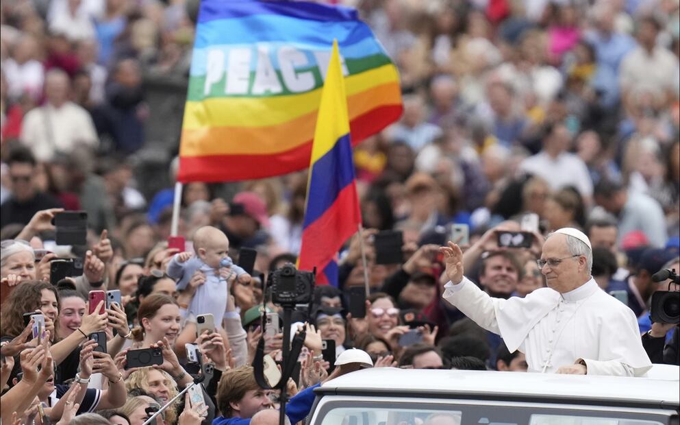 El papa León XIV saluda a una multitud, con una bandera de la paz de fondo reunida en la Plaza de San Pedro, el 21 de mayo de 2025. Foto: AP