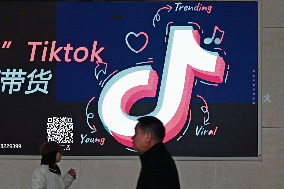 Lugareños, junto a un anuncio con el logotipo de TikTok en una estación de tren en Zhengzhou, en la provincia central de Henan, China Foto: Greg Baker / AFP