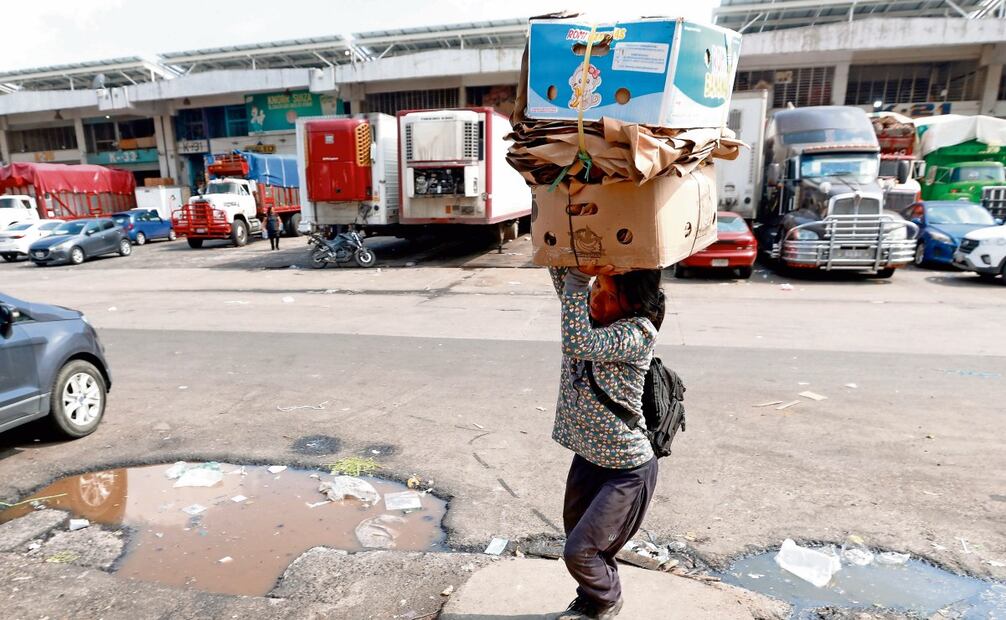 Mientras ella va y viene con su carga, muchos hombres esperan en lo alto de los camiones, observando el botín. Foto: Diego Prado / EL UNIVERSAL
